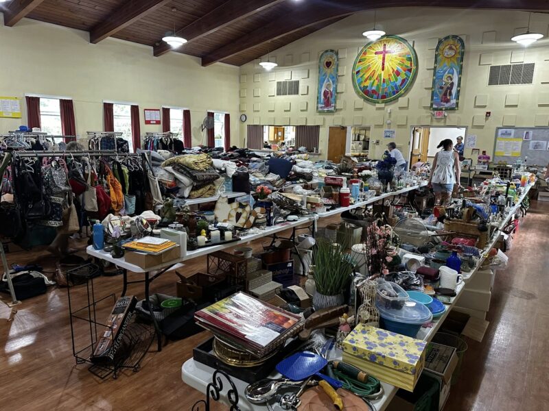 Fellowship Hall filled with Rummage Sale items like clothes, household goods, toys and decorations.